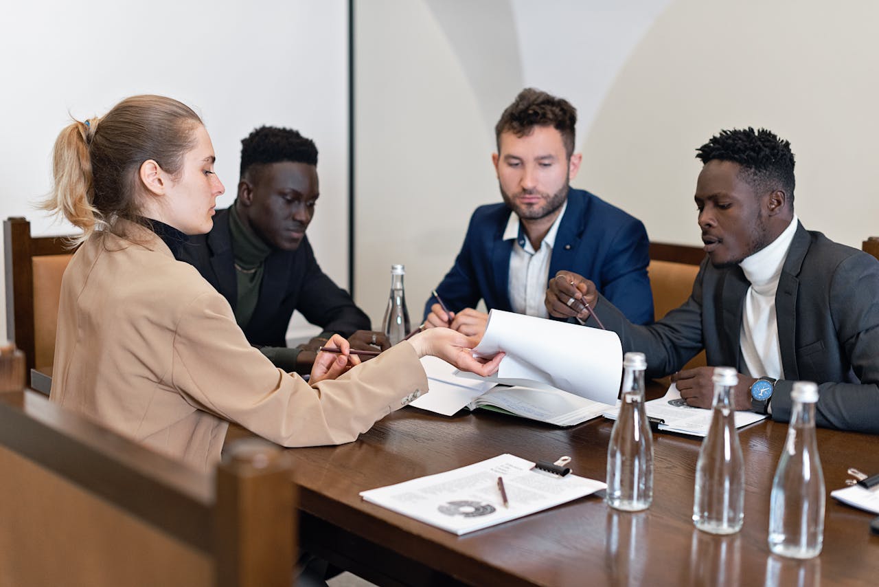 Business team in office meeting discussing contracts with diverse representation.